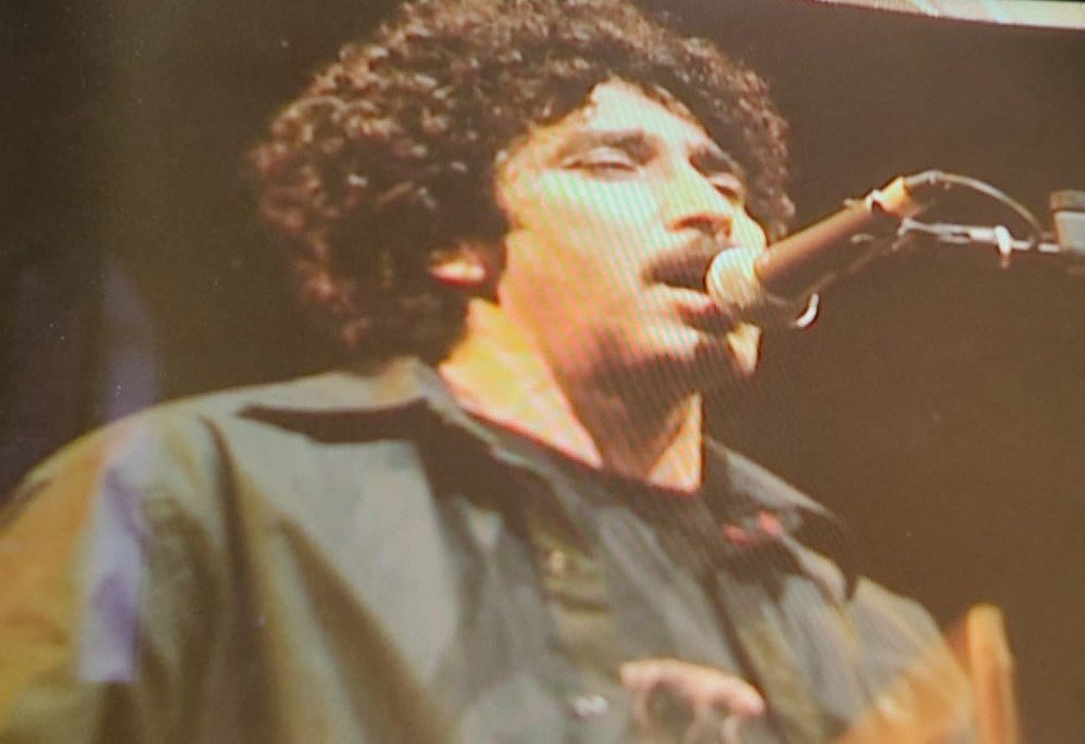 A curly-haired Nass El Ghiwane singer at the microphone